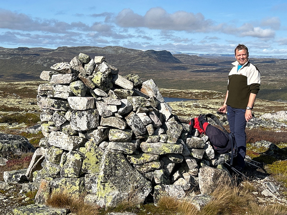 Nils og en gedigen varde på Ryltesteinbrotet. I bakgrunnen er Bjordalsnutan midt i bildet foran enda fjernere fjell.