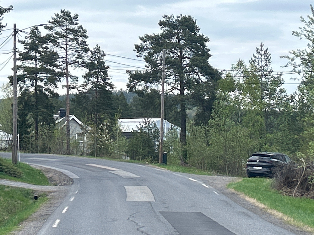 Bilen min parkert ved Fjellsveien. Tårnet på Nordbykollen kan skimtes i bakgrunnen mellom furutrærne.