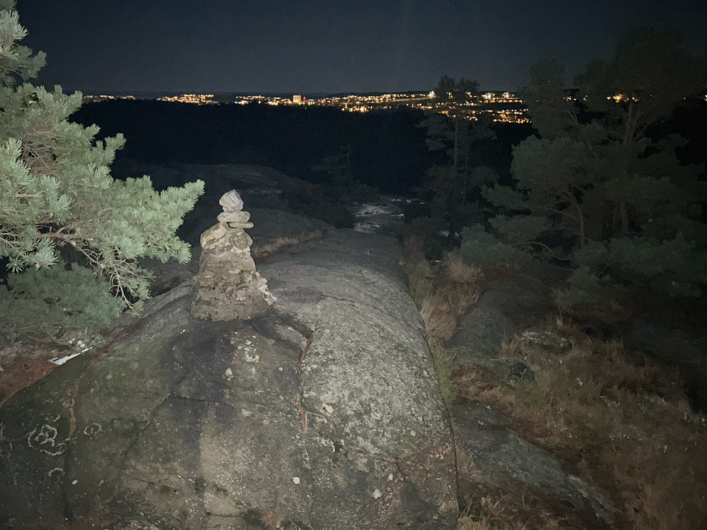 Toppen av Hellerstønuten med lysene fra Kristiansand i bakgrunnen.