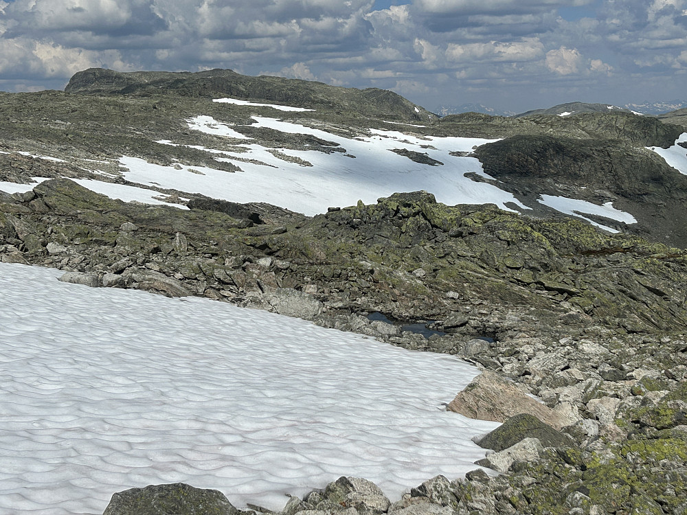 Og for å unngå en del stein, valgte vi å holde høyden sånn noenlunde, og heller gå over snøfeltene bortover mot Gråhyrneranmassivet litt til venstre i bildet.