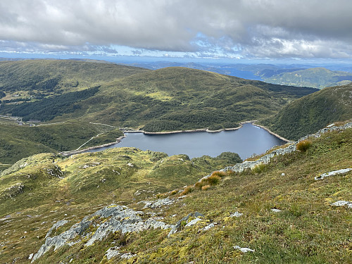 Bilde #9: Utsikt fra Ronamanen [889 m.o.h. ned mot Svartavatnet [408 - 381 m.o.h.] med demningen. Til venstre i bildet sees parkeringsplassen ved Osavatnet, og i høyre billedhalvdel kan man se utover Sørfjorden like ut til Knarvik.