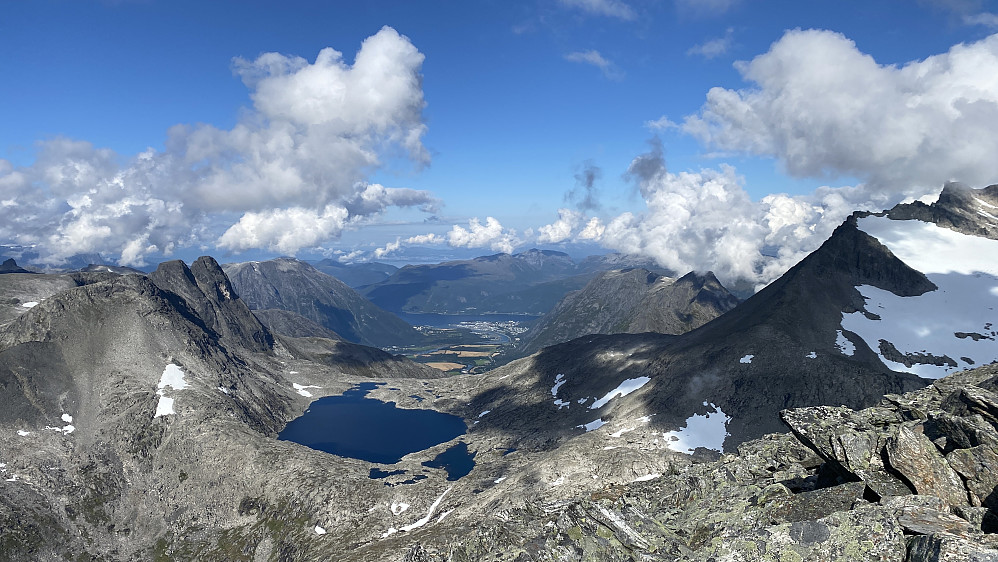 Bilde #7: Utsikt mot Åndalsnes. Vatnet like til venstre for midten av bildet er Olaskarsvatnet [1028 m.o.h.]. Til venstre for vatnet sees Olaskartinden [1536 m.o.h.], Hornaksla [1511 m.o.h.], Litjhornet [1538 m.o.h.] og Romsdalshornet [1550 m.o.h.]. Til høyre for vatnet sees Venjetindtraversen med bl.a. Søre Venjetind [1729 m.o.h.] og Lille Venjetind [1822 m.o.h.]. Åndalsnes sees i det fjerne. Romsdalseggen med Blånebba [1320 m.o.h.] og Mjølvafjellet [1216 m.o.h.] sees til høyre for Åndalsnes. Til venstre for Åndalsnes sees Setnesfjellet [1238 m.o.h.].