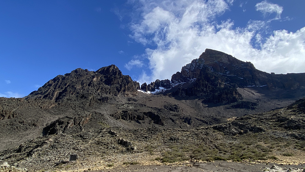 Image #39: Mawenzi with its many peaks as seen from the Tarn Hut. The ridge forms a semicircular shape, as it is the remains of an old volcanic crater. The other half of the crater ridge has been eroded away for a long time.