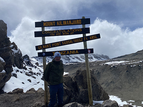 Image #46: Me at Gilman's Point. The summit [i.e. the Uhuru Peak] is hidden behind the sign. The mountain to the right is Kibo, the other peak of Kilimanjaro.