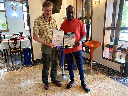 Image #75: Frank handing over to me one diploma for the Kilimanjaro ascent, and another for the Meru ascent.