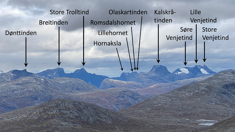 Bilde #9: Utsikt fra Raumyrhøa [1616 m.o.h.] mot fjella i området omrking Åndalsnes. I tillegg til de som er nevnt på bildet, sees Kvanndalstinden som en mørk skygge foran Lille Venjetind, og Nordre Trolltind sees som en karakteristisk knaus på fjellryggen nordøst for Store Trolltind. Knausen mellom Olaskartinden og Kalskråtinden er "Søre Kalskråtinden".