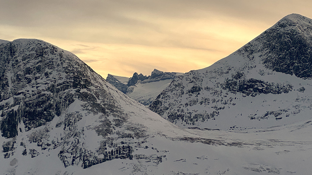 Bilde #11: Trollveggen med blant annet Breitinden, Trollryggen, Trollspiret, Trollgubben, Trollkjerringa og Store Trolltind kommer tilsyne mellom Gravfjellet og Smørbottinden. Nedenfor Store Trolltind sees også Adelsbreen, Adelsfjellet og Nordre Trolltind.