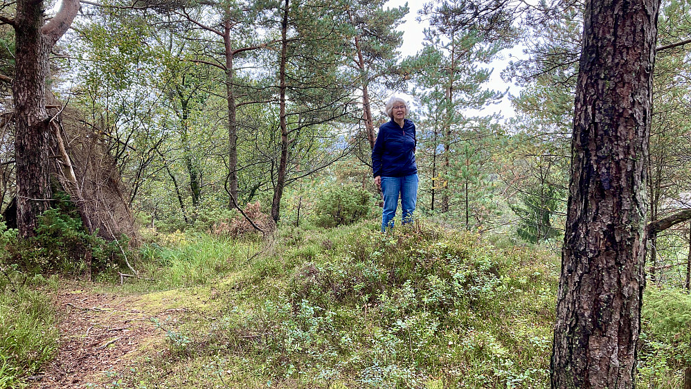 Astrid på toppen av Storahugen. Rester etter hytte mot venstre