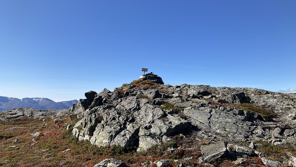 Toppen på Ljosandberget 1178. Kasse med turbok og påle med skilting til turmål i nærheten ved en annen varde noen meter nord for toppen