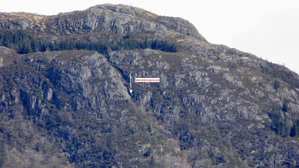 Zoom mot Manndomsprøven på Løvstakken fra kjøkkenvinduet hjemme. Storhaugen 469 og skogen rundt Tjødnet med Djevel-steinene i bakgrunnen. Foto Helge S. Titland