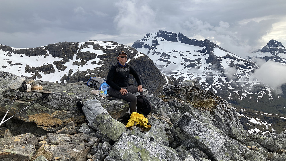 Matpause på bart fjell før vandring i snø. Foto mot sør. Sannsynligvis Snøtinden 1215 mot venstre og Ristingen 1055 mot høyre i bakgrunnen