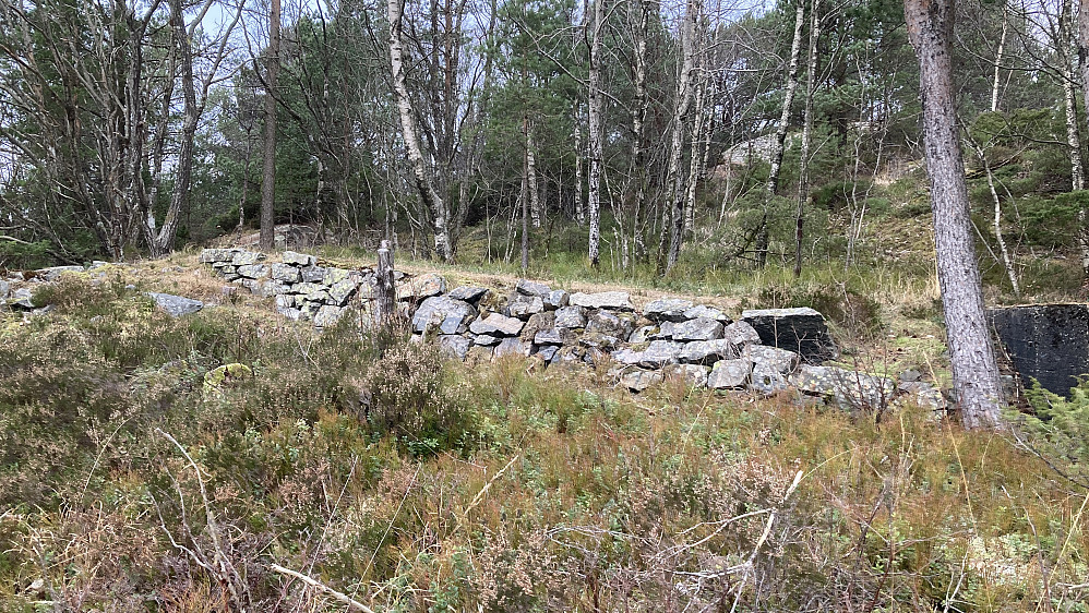 Mur ved øvre ende av taubanetraséen. Rester av grunnmur etter bygning mot høyre