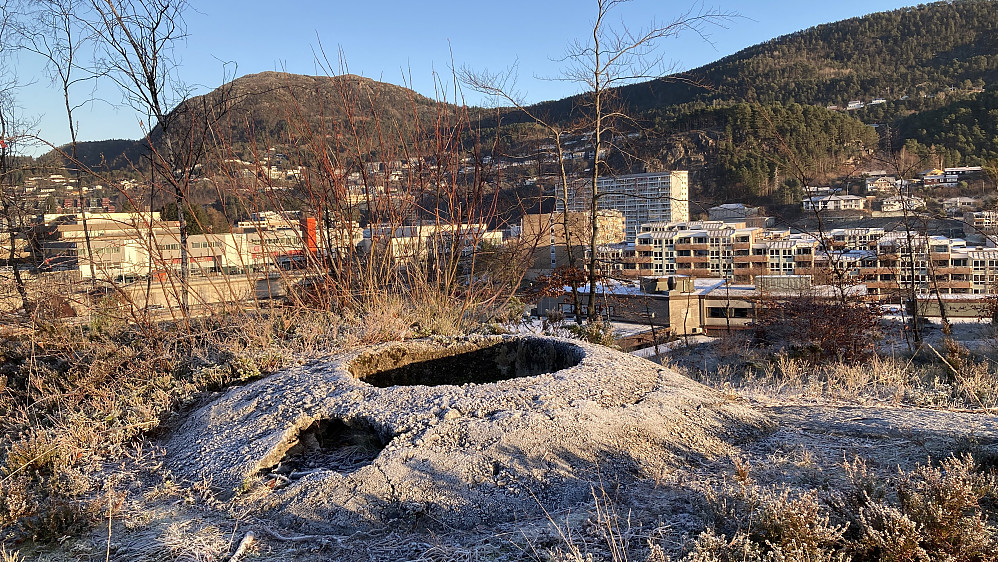 Skytestillingen på haugen øst for Skulehaugen. Løvstakken i bakgrunnen. Defekten i betongen er etter et gjerde brukt under tidligere byggearbeid for blokkene nedenfor