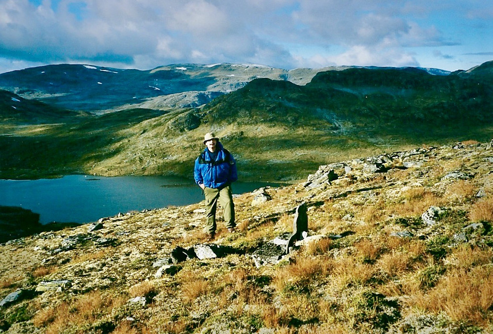 Helge ved fangstmannsgraven og gravstøtten reist av Helge.  Foto mot Soleifletvatnet i nord. Rognaldsnosi med Skammadalshøgdi i bakgrunnen 