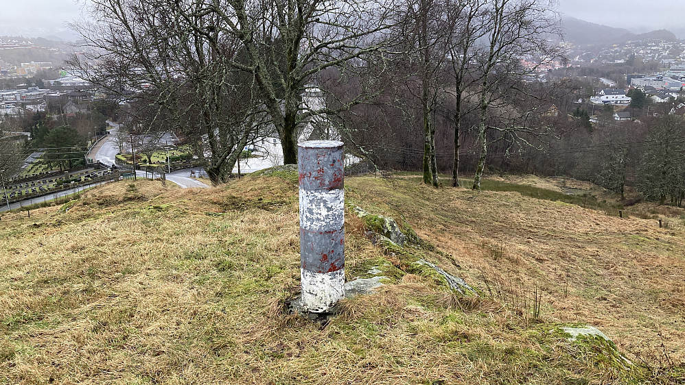 Saurås søyle. Gamle Åsane kirke i bakgrunnen