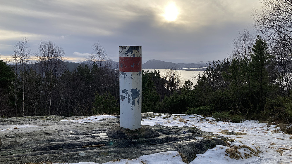 Søylen står flott til på en liten haug vest for de øverste husene i Myrdalskogen. Lyderhorn skimtes i bakgrunnen