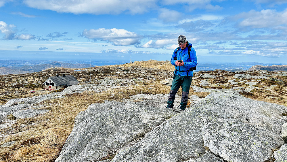 Helge på en fjellknaus som sannsynligvis er høyeste punkt på Haukelandstikkene. Dette er et grenspunkt markert med en jernbolt omtrent midt i bildet. Turnerhytten mot venstre og Ulriksmasten i bakgrunnen.