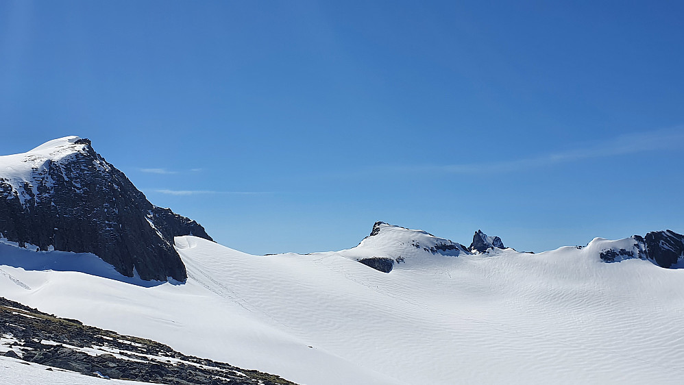 Oppe på toppryggen mot Sjøvdøla. Mot Bliksskårstind, Nyheitind og Juratind.