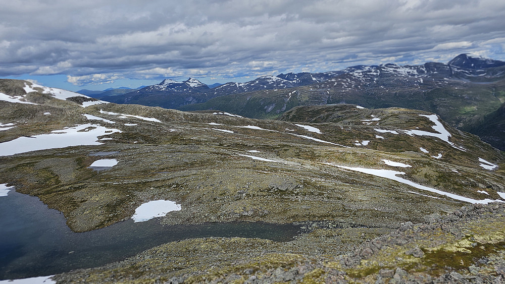 Veien videre. Krysser utløpet fra vannet, og går mott toppene bak til høyre.