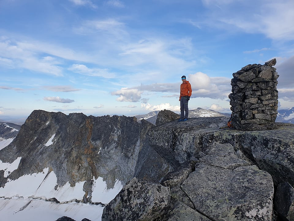 Bilde av Marius på toppen av Store Memurutind Vesttoppen. Siste topp 16/16, hurra! Til vestre ser man tilbake på rekka vi hadde gått. Nå gjensto bare nedmarsjen til teltet.   