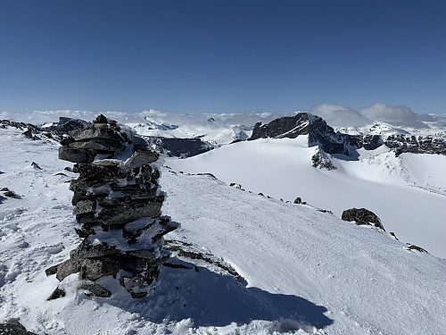 Fra Veslepiggen (2369 m) mot Storjuvbrean og Skardstinden (2373 m). Enkelte fjelltopper i Jotunheimen skimtes opp av det lavtliggende skydekke.