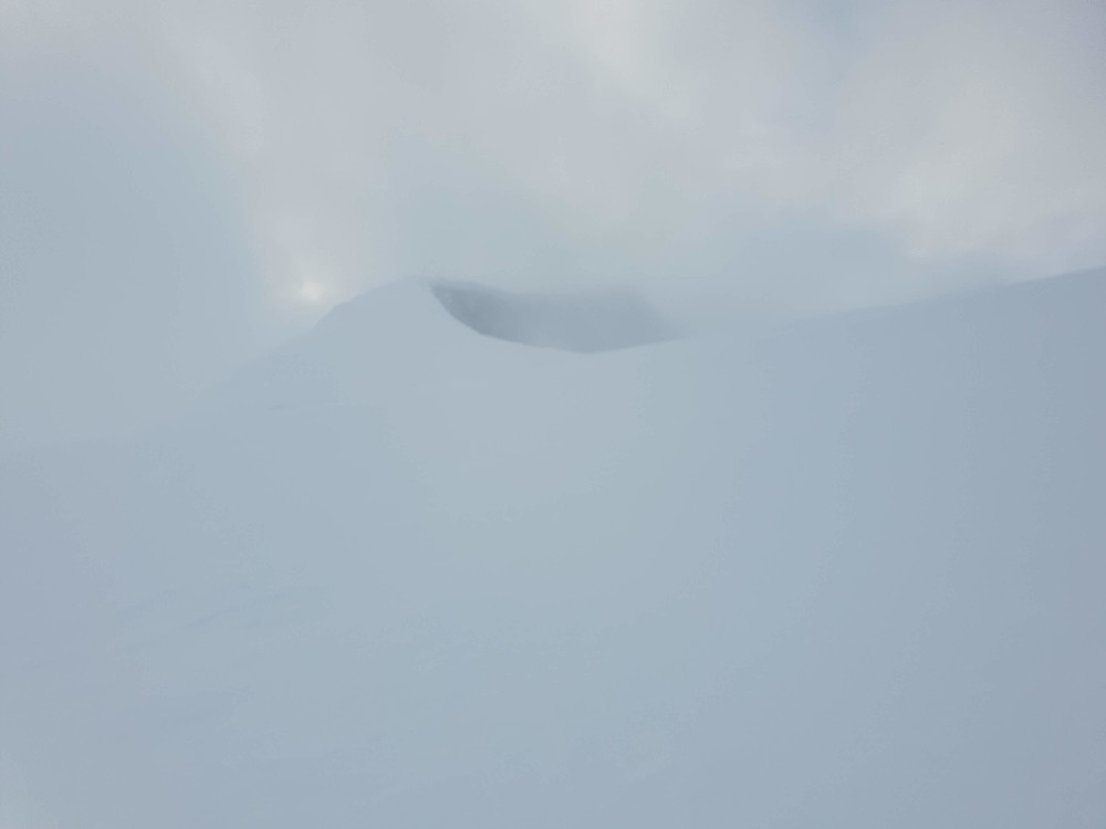 Austre Holåtinden skimtes gjennom skyene.