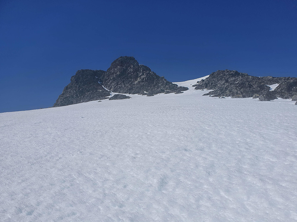 Opp sørsida på Mjølkedalstinden. Bratt snøbakke oppover. Gikk opp snøtarmen til høyre i øvre del av bildet. Deretter 20-25 meters klyveparti til venstre mot sørryggen. Sikret gjestene her fra en solid nabb.