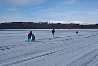 Isfiskere som jakter etter storrøya på Øvrevann. Uhcagágga ses bak til høyre.
