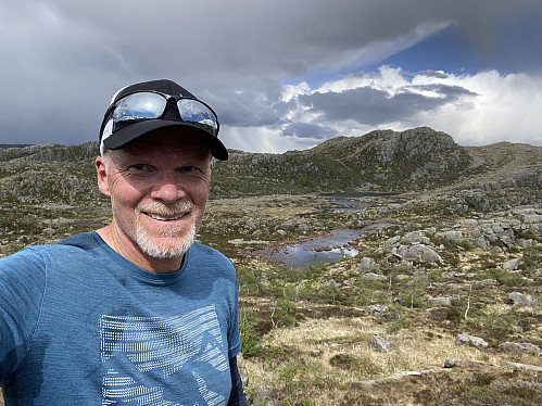 Fornøyd på tur til tross for kupert terreng! Steintjørna og Harafjellet danner bakgrunnen