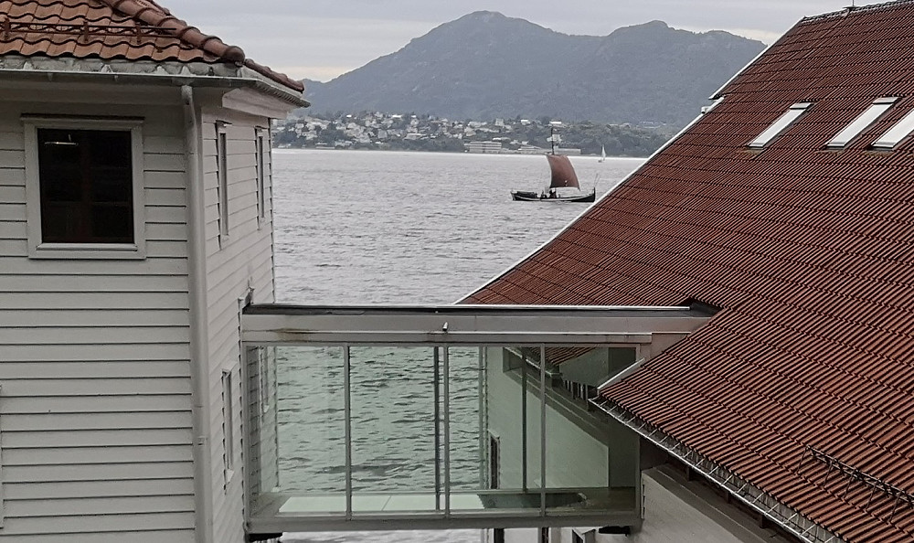 Litt av Grønnlandsboden anno 1720 med en nordlandsbåt med fulle seil utenfor