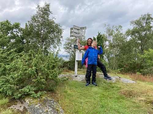 Trigpunktmerke og glade turfolk på toppen av Storafjellet