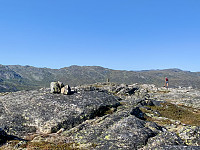 Topp-punktet på 1143 m markert med tre steiner. Varden, som står på 1140 m, i bakgrunnen.