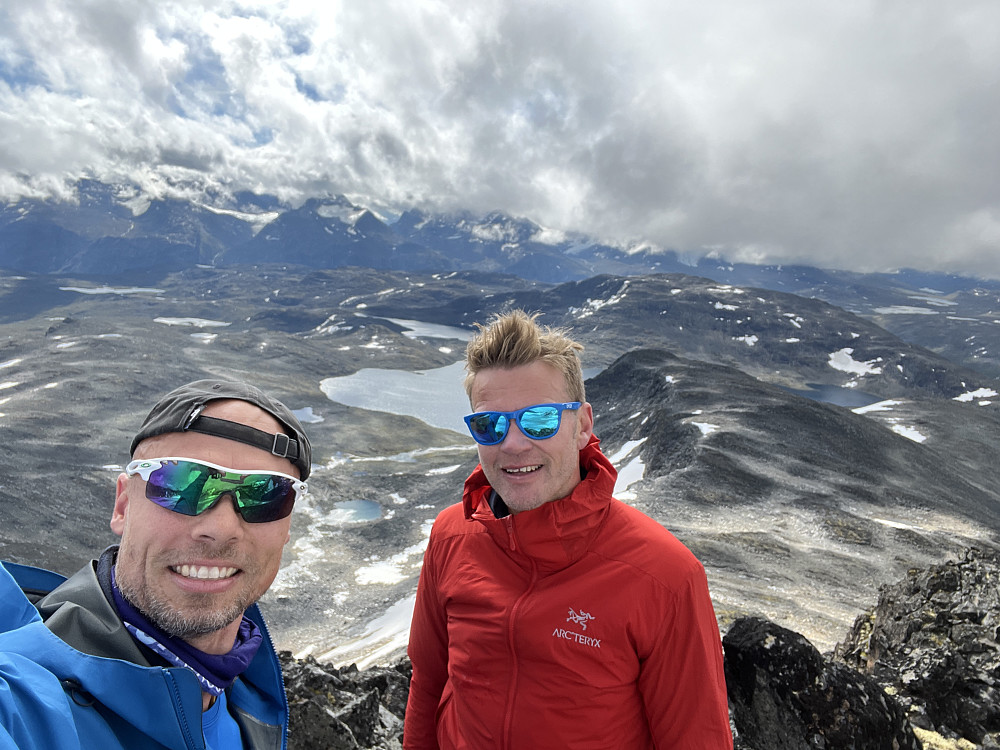 Selfie med Oddbjørn og meg selv på toppen av Hinnotefjellet. I bakrunnen Hinnotetjønn og Gjendealpene oppe i skyene.