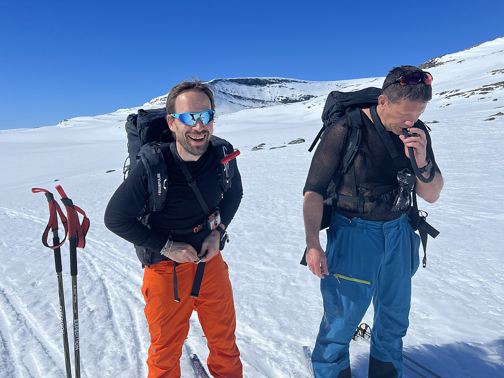 Frode og Jan-Trygve drikker litt og justerer litt på sekken. I bakgrunnen ser vi den skarpe østveggen på Blåhøe.