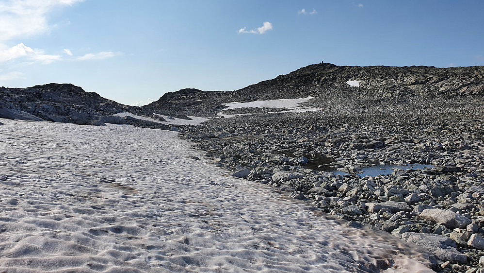 På snøfonner mot toppen av Blåbergi. Trig.punktet (1802) med den synlige varden oppe til høyre. Noe lengre bak og litt til venstre ses Blåbergi Vest (1801).