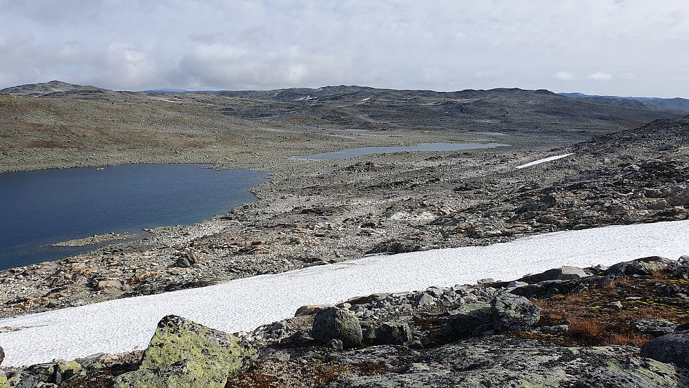 Vi er på høyden sør for Skavlevatnet, som er vannet til venstre. Midt i bildet bakerst, ses de to jevnhøye toppunktene på Sørøst for Einarsvatnet (1709). Den til høyre er toppen.
