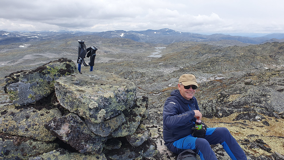 Erling tar en velfortjent hvil ved toppvarden på Lærdalseinaren (1715). Det høye fjellet i bakgrunnen nesten midt i bildet, er Store Hånosi (1836).