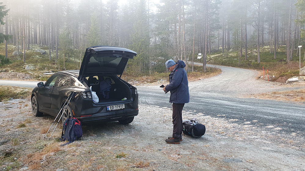 Vi gjør oss klare for tur på parkeringen. Veien som går opp til Nuten forsvinner oppover i skogen til høyre for Øyvind.