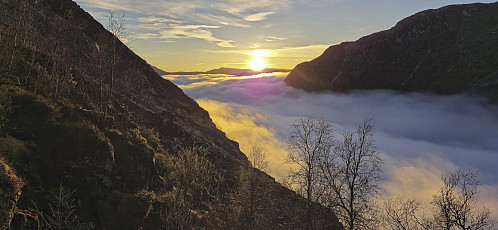 The sun setting above the fog during the descent